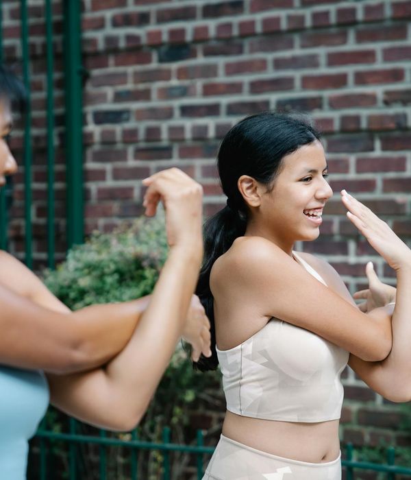 Happy woman in light activewear stretching outdoors.